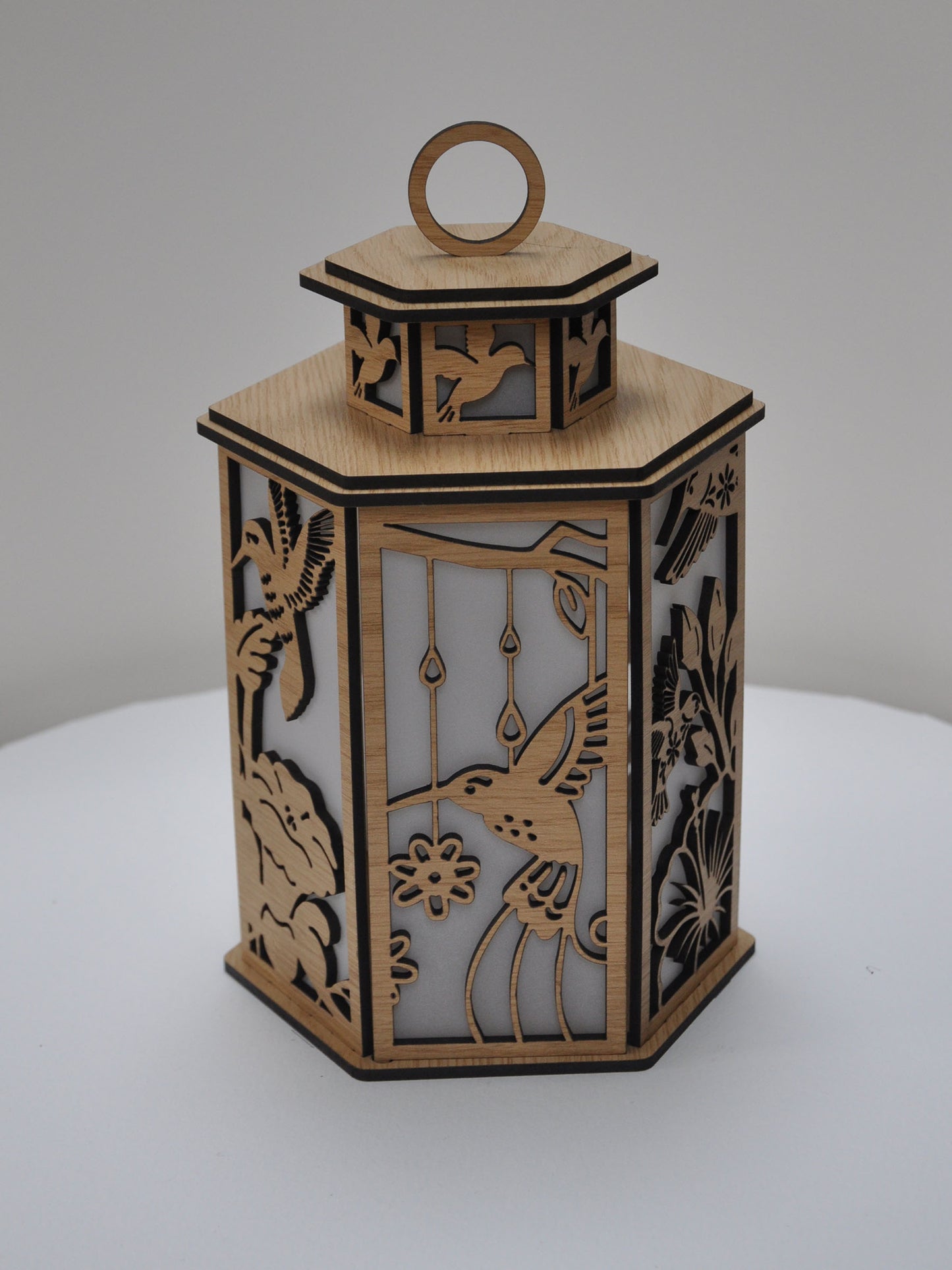 Decorative wooden lantern with intricate cut-out designs on a white background