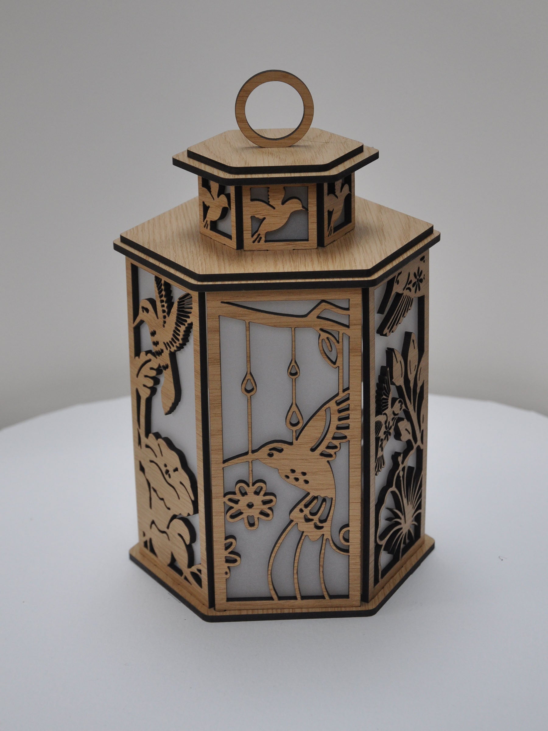 Decorative wooden lantern with intricate cut-out designs on a white background